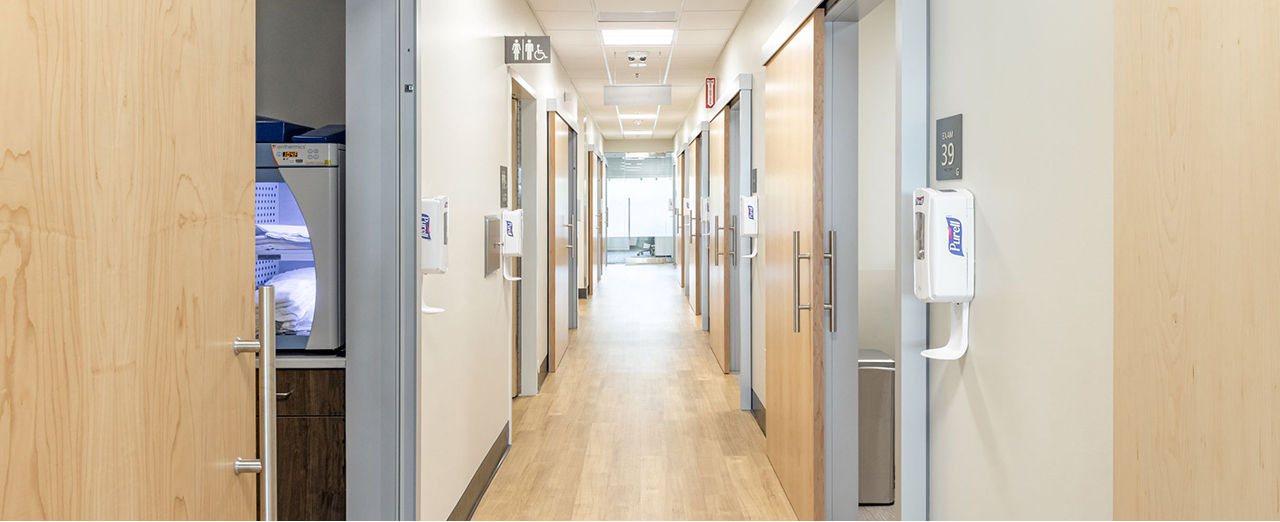 Hospital hallway showcasing wooden doors against a white wall, designed for patient room access and safety.