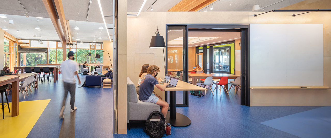 Open school area with bright blue floors and sliding glass classroom doors separating rooms.