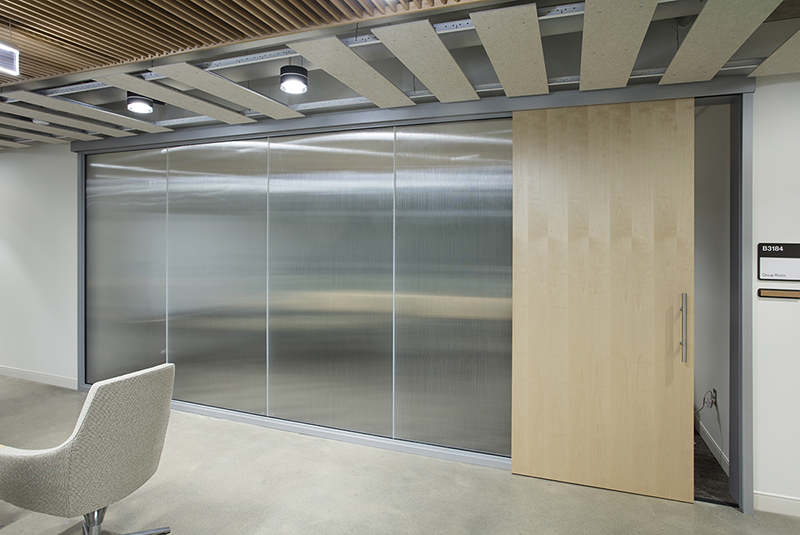 Flush wood sliding door leading to a conference room with frosted glass panels.