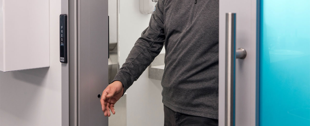 Person using a hands-free control to operate an interior automatic sliding door.
