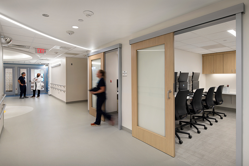 Hallway with large open ADA-compliant door and a desk, designed for healthcare settings.