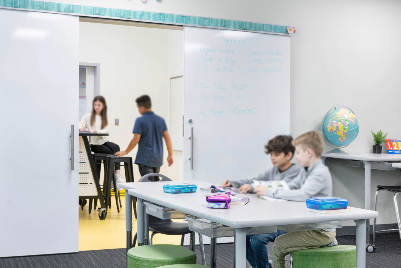 Modern educational classroom with flexible learning spaces, featuring sliding doors and mobile furniture.