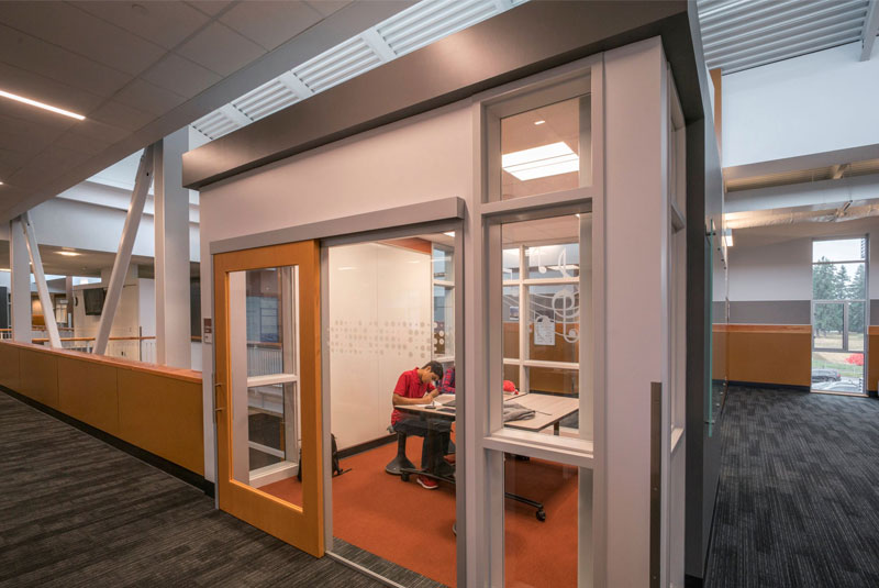 Spacious flexible classroom with sliding glass doors connecting to a common area, promoting collaborative learning.