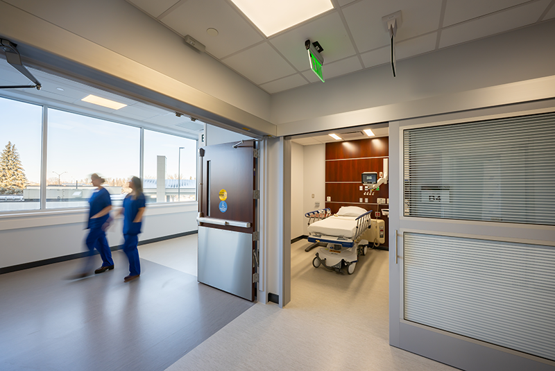 A medical office setup including a desk, chair, computer, and sliding door systems for efficient patient flow.